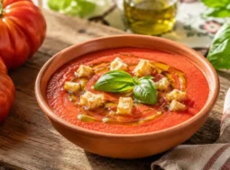 Una ciotola di gazpacho all'italiana guarnita con crostini di pane e un filo d'olio d'oliva