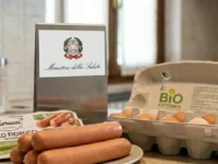 Prodotti alimentari sul tavolo di una cucina con in primo piano una confezione di würstel Fiorucci e uova fresche, affiancati dal logo ufficiale del Ministero della Salute per un avviso di richiamo.