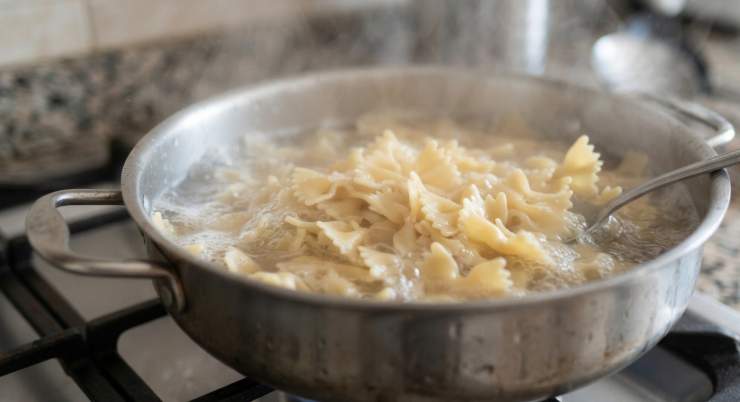 Portate a ebollizione una pentola con abbondante acqua, salate e versate le farfalle. Cuocete la pasta scolandola rigorosamente al dente (1-2 minuti prima rispetto al tempo indicato sulla confezione). Scolate la pasta senza passarla sotto l’acqua fredda (questo è il trucco fondamentale per mantenere l’amido che farà aderire il condimento!), conditela con un filo di olio extravergine d’oliva e disponetela allargata su una teglia per farla raffreddare rapidamente a temperatura ambiente.