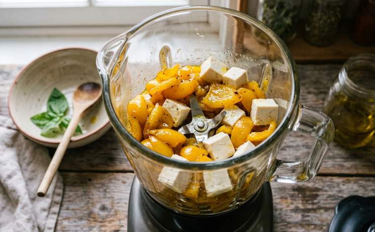 Nel frattempo, portate ad ebollizione una pentola abbondante di acqua, salatela e calate la vostra pasta preferita, cuocendola al dente. Trasferite i peperoni cotti nel bicchiere di un frullatore a immersione, unite il tofu vellutato e frullate il tutto fino ad ottenere una crema liscia, vellutata e omogenea. Se necessario, aggiustate ulteriormente di sale. Scolate la pasta tenendo da parte un goccio di acqua di cottura. Conditela subito con la vellutata crema di peperoni, spolverate con abbondante prezzemolo fresco tritato e servite ben calda.