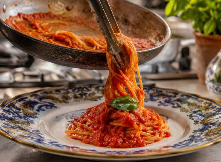 Quando gli spaghetti saranno perfettamente al dente, spegnete il fuoco. Aggiungete un generoso giro d’olio extra vergine d’oliva a crudo e un’abbondante manciata di foglie di basilico spezzate a mano. Mantecate energicamente muovendo la padella per creare un’emulsione lucida, cremosa e irresistibile.