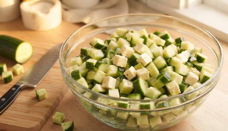 Prendete il panetto di feta, sbriciolatelo grossolanamente con le mani oppure tagliatelo a cubetti della stessa dimensione dei cetrioli, quindi unitelo nella ciotola. Condite il tutto distribuendo uniformemente l’olio extravergine d’oliva, un pizzico di sale, l’origano secco e una macinata di pepe nero.