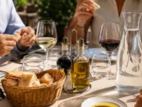 Oliera in vetro trasparente con beccuccio di metallo su un tavolo al sole di un ristorante