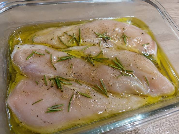 Iniziate con la marinatura del pollo, passaggio chiave per mantenerlo succoso: adagiate i petti di pollo in una pirofila, irrorateli con il succo di limone, due cucchiai di olio extravergine d’oliva, un pizzico di sale, pepe nero e gli aghi di un rametto di rosmarino. Lasciate riposare in frigorifero per circa 15/20 minuti.