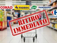 Carrello vuoto al supermercato con timbro rosso Ritiro Immediato e loghi di Conad Carrefour Tigros e Pam