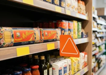 Scaffale di un supermercato italiano con pacchi di pasta e un cartello arancione di segnalazione per la shrinkflation