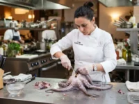 Chef professionista in cucina mentre pulisce un polpo fresco su un tavolo di acciaio