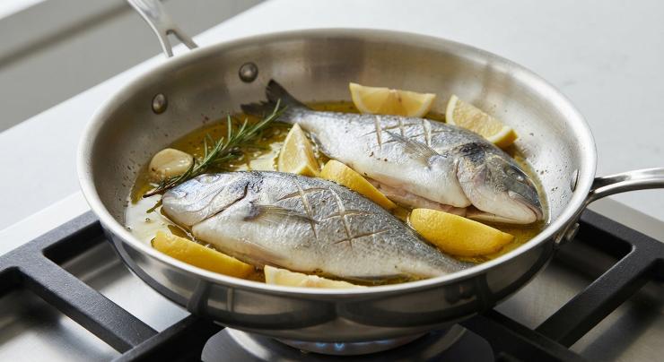 In una padella capiente o in un tegame, versate un giro generoso di olio extravergine di oliva. Aggiungete l’aglio rimasto leggermente schiacciato e un rametto di rosmarino. Scaldate a fuoco dolce per far insaporire l’olio. Adagiate le orate nel tegame, disponetele con cura e aggiungete qualche spicchio di limone fresco intorno al pesce. Regolate di sale e pepe anche la superficie esterna.