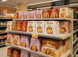 Scaffale di un supermercato con panettoni di marche famose esposti in anticipo a ottobre.